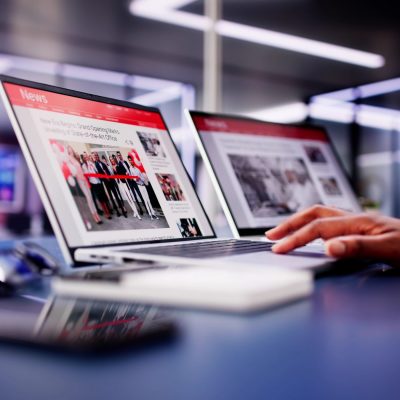 American,Woman,Views,Online,News,Articles,On,Laptop,And,Phone